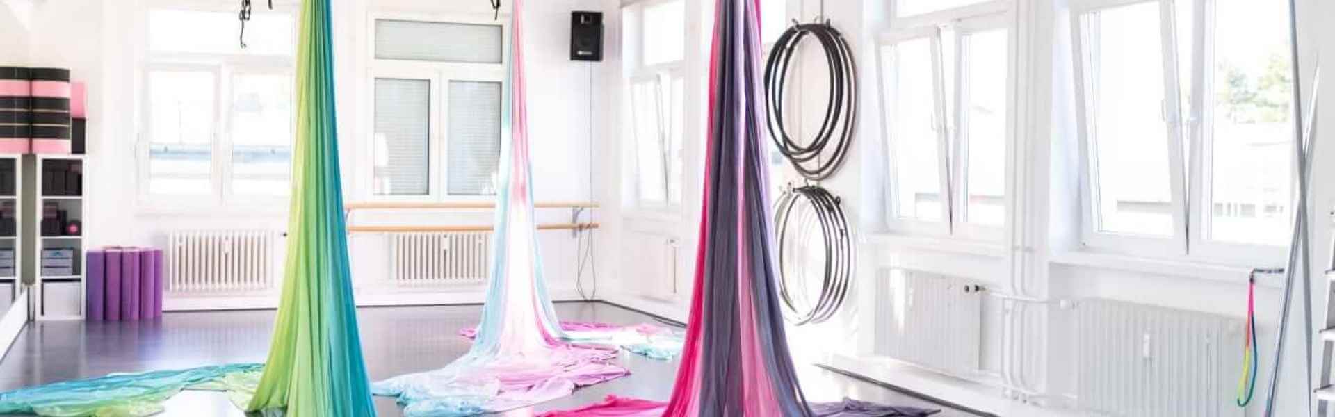 Luftakrobatik-Tücher in bunten Farben hängen im hellen Aerial-Studio